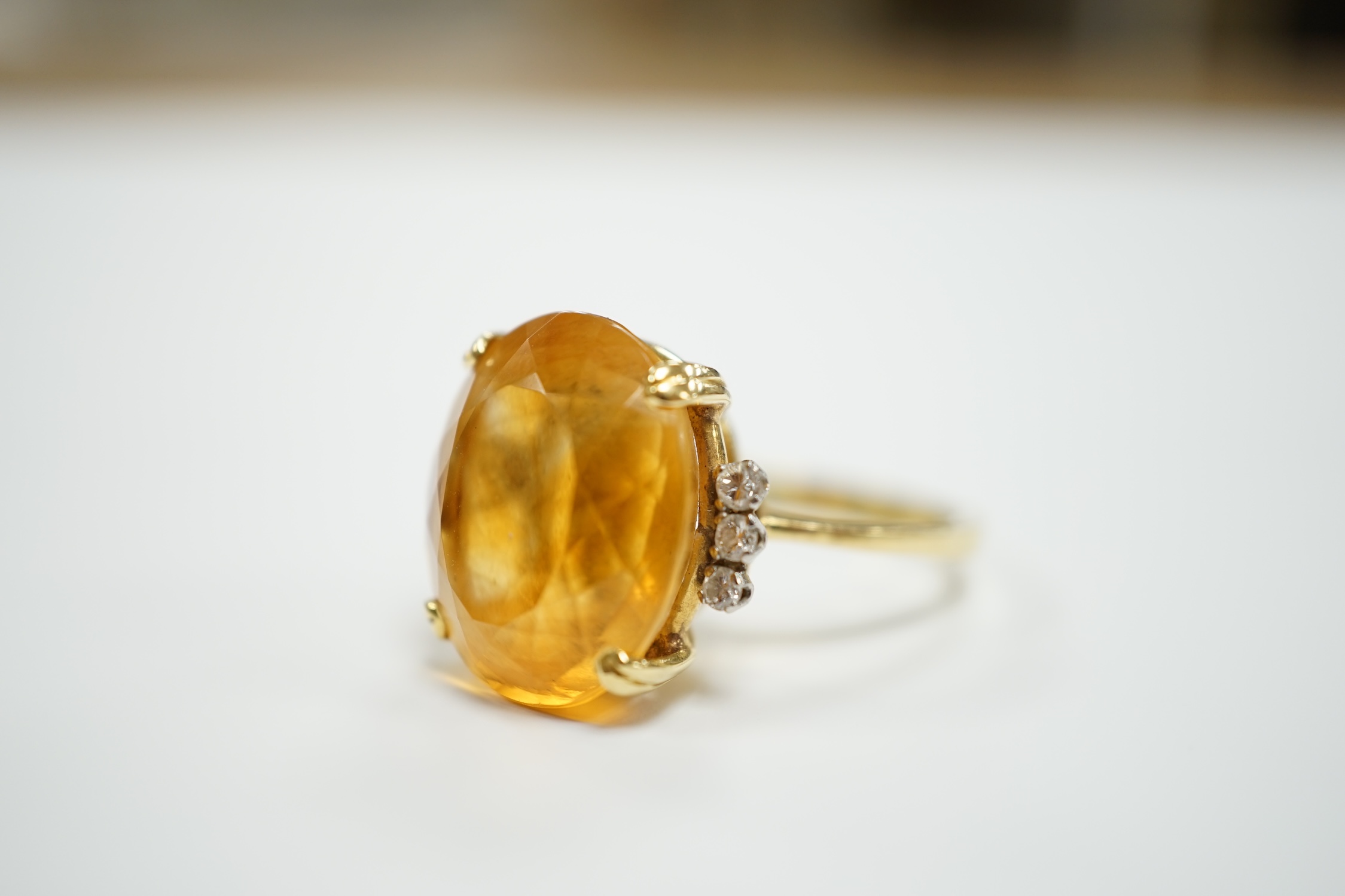 An 18k and single stone oval cut citrine set dress ring, with six stone diamond set shoulders, size R, gross weight 8.3 grams.